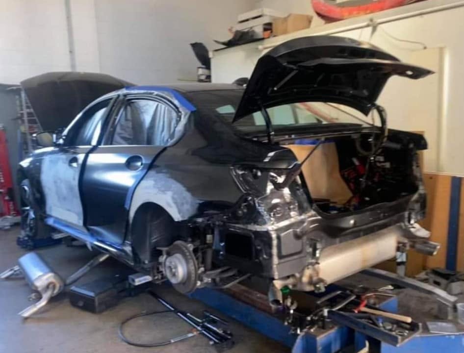 A BMW 3 Series on the hoist with the rear quarter stripped back for accident repair