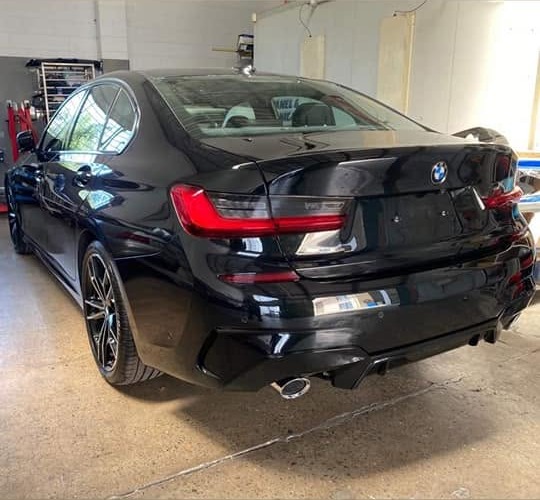 Finished black BMW 3 Series, rear view, in the workshop