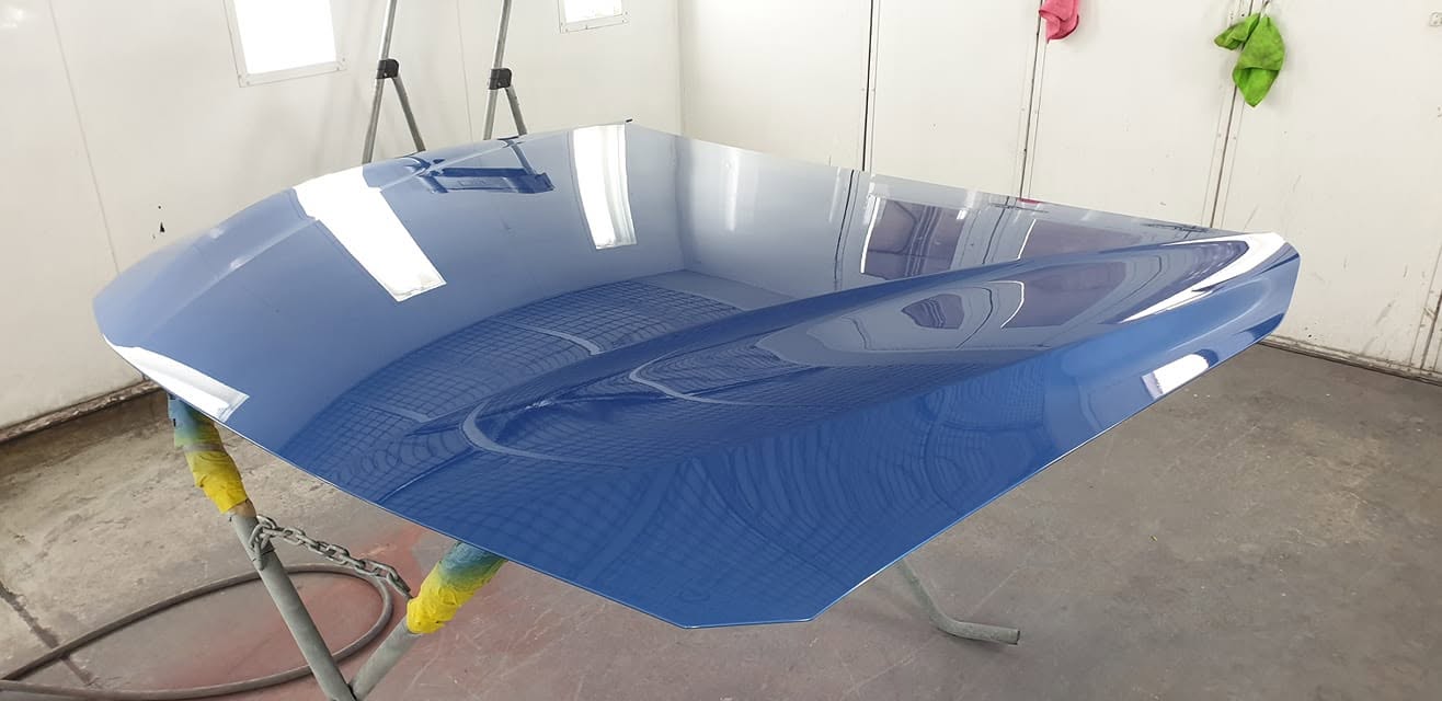 A freshly resprayed blue BMW bonnet with a glass-like finish in the spray booth