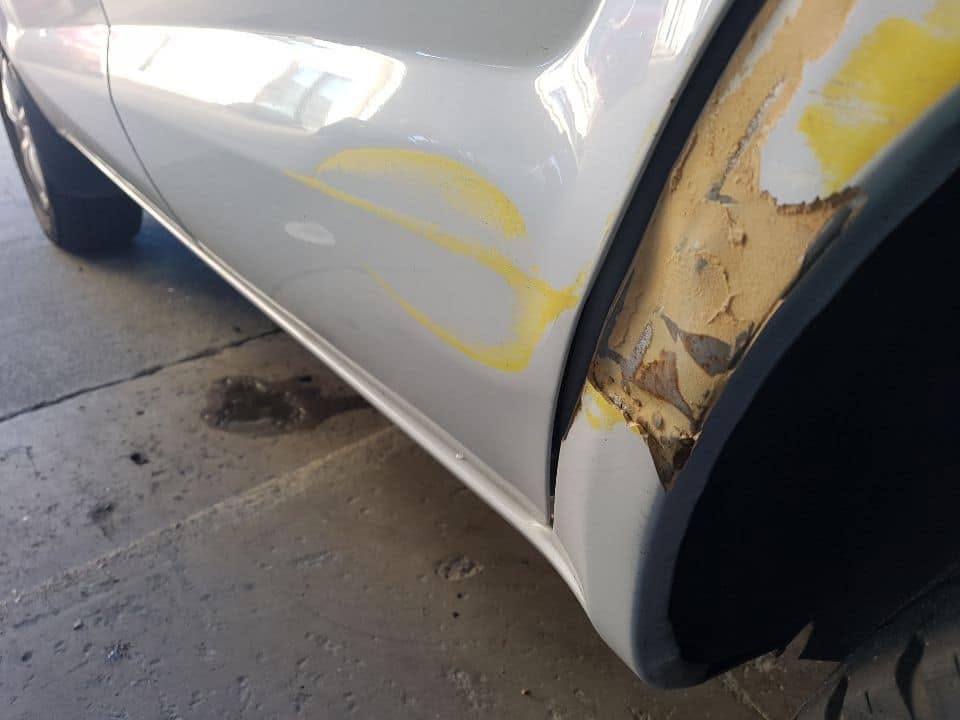 Rust damage on a rear wheel arch before repair