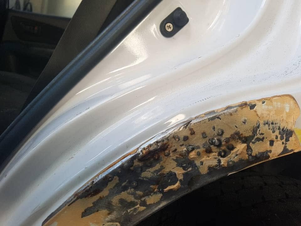 A rusted wheel arch stripped back to bare metal