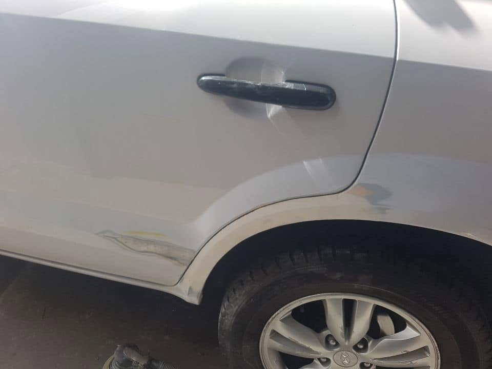 A repaired and repainted rear wheel arch on a white car