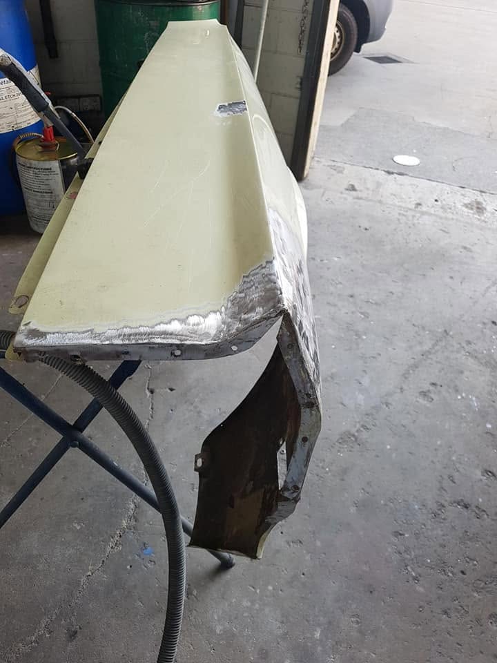 A hand-fabricated replacement panel for a classic car on a stand