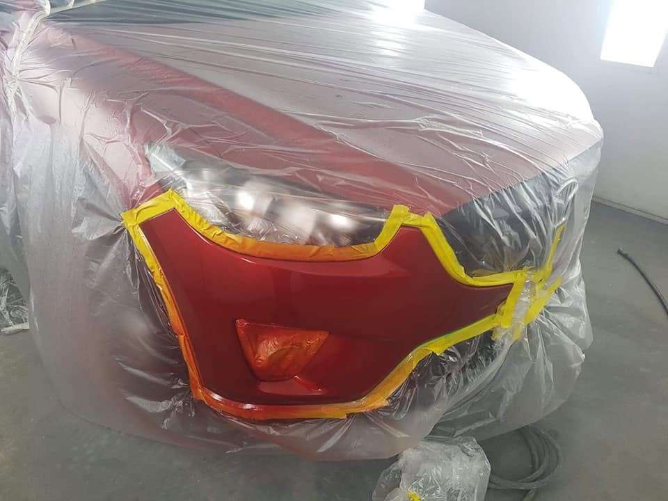 A red car masked up around the tail light ready for paint