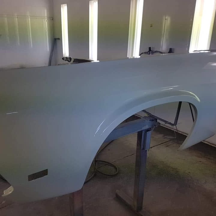 A silver panel in primer in the spray booth