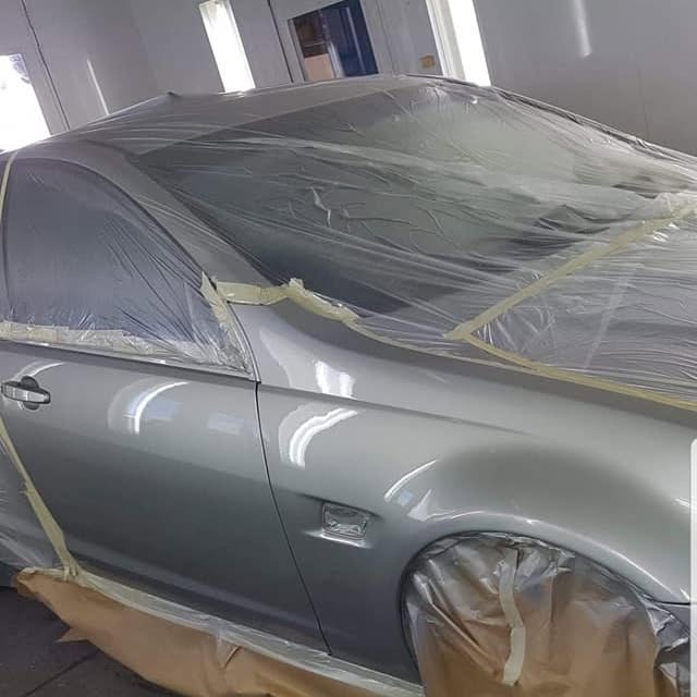 A silver car masked up and primed ready for paint
